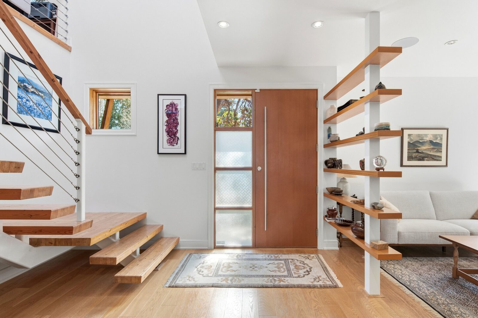 Entry with custom wood door, open staircase, and oak shelving